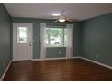 A bright living room with a ceiling fan, wood flooring, and a large window offering plenty of natural light at 8655 Sw 98Th Street Rd # G, Ocala, FL 34481