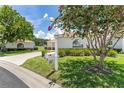 View of a well-maintained home exterior featuring landscaped grounds, a mailbox, and mature trees at 8689 Se 141St Street Rd, Summerfield, FL 34491