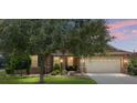 Inviting home exterior with a well-maintained lawn, mature shade tree, and warm, inviting lighting at 9222 Sw 97Th Cir, Ocala, FL 34481