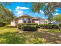Side view of a charming single-story home featuring a two-car garage, well-maintained landscaping, and a light beige stucco exterior at 9746 Sw 89Th Loop, Ocala, FL 34481