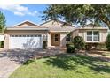 Beautiful home showcasing a well-maintained lawn, brick driveway, and classic architectural design at 9926 Sw 95Th Loop, Ocala, FL 34481