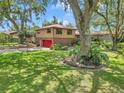 Home with a red roof, beautiful front lawn, and mature shade trees in a residential setting at 2676 Se 52Nd Ave, Ocala, FL 34480
