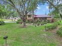 Home featuring a red roof, manicured front yard, and mature trees creating a welcoming entrance at 2676 Se 52Nd Ave, Ocala, FL 34480