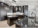 Modern kitchen featuring dark wood cabinets, stainless steel appliances, marble countertops, and a stylish chandelier at 3440 Sw 66Th St, Ocala, FL 34476