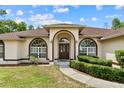 Close-up of the front entrance, showcasing arched double doors and manicured hedges leading to the home at 4973 Sw 107Th Loop, Ocala, FL 34476