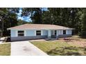 Beautiful light blue single-story home with white trim, brick base, and manicured lawn at 6475 Nw 61St Ave, Ocala, FL 34482