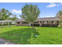 Charming single-story home featuring manicured lawn, brick accents, covered parking, and a mature shade tree at 713 Se 34Th Ter, Ocala, FL 34471