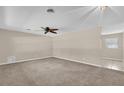 Spacious living room with neutral-toned walls, ceiling fan, and plush carpet flooring at 713 Se 34Th Ter, Ocala, FL 34471