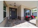 Cozy covered porch features a pendant light, door with sidelights, and comfortable seating area at 9746 Sw 108Th Terrace Rd, Ocala, FL 34481