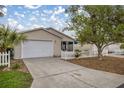 Inviting home with a well-manicured front yard, a picket fence, and an attached garage at 1405 Espinoza Ln, Lady Lake, FL 32159