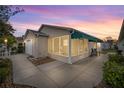 Cozy home exterior view featuring a screened-in lanai with ample outdoor seating under an elegant awning at 1405 Espinoza Ln, The Villages, FL 32159