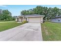 Single story home with a spacious driveway, attached garage and manicured lawn at 14650 Sw 33Rd Ln, Ocala, FL 34481