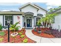 Inviting front entrance with a decorative door, colorful landscaping, and a charming walkway at 19115 Sw 98Th Loop, Dunnellon, FL 34432