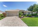 Beautiful home with manicured lawn, paver driveway, and lush landscaping creating curb appeal at 3001 Hillside Ln, The Villages, FL 32162