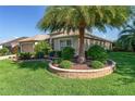 Home with lush, green lawn and tropical landscaping featuring a palm tree in a stone planter at 3001 Hillside Ln, The Villages, FL 32162