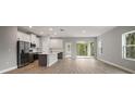 Bright open-plan living area with wood-look floors, a kitchen island, and sliding glass doors at 5 Larch Course Ter, Ocala, FL 34480