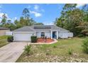 Charming single-story home with a well-maintained front yard, blue door, and attached two car garage at 603 Marion Oaks Blvd, Ocala, FL 34473