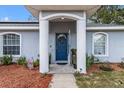 Inviting front entrance with an arched entryway, a blue front door, and lush landscaping at 603 Marion Oaks Blvd, Ocala, FL 34473