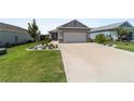 Well-manicured front yard showcasing lush green grass, landscaped area, and long driveway leading to the two-car garage at 8905 Sw 76Th Ln, Ocala, FL 34481