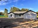 A cozy one-story house with a two-car garage, set against a backdrop of tall trees at 5 Willow Trl, Ocala, FL 34472
