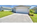 Single story home featuring an attached two car garage and concrete driveway, perfect for parking at 2123 Cartgate Lane, Winter Haven, FL 33884
