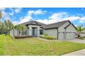 One-story house with gray exterior, three-car garage, and lush landscaping at 4940 Tennessee Lake Dr, Auburndale, FL 33823