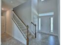 Bright foyer boasts soaring ceilings, a staircase with wood handrail, neutral decor and decorative tile flooring at 1476 Leamington Lane, Winter Haven, FL 33884