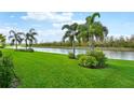 Lush green lawn, palm trees, and a serene canal view at 473 Adams View Ln, Auburndale, FL 33823