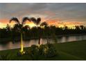 A captivating backyard view featuring an orange sunset over the canal and elegant landscape lighting at 473 Adams View Ln, Auburndale, FL 33823