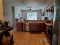 Functional kitchen boasts stainless steel appliances, wood cabinetry, and tile flooring at 2712 Oak Hammock Loop, Mulberry, FL 33860