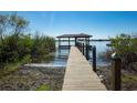 Picturesque view of a private dock extending into a tranquil lake with a covered pavilion on stilts at 4027 Island Lakes Dr, Winter Haven, FL 33881