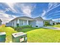 One-story house with a two-car garage, and a green lawn at 566 Valentina Ln, Auburndale, FL 33823