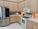 Well-maintained kitchen with stainless steel refrigerator, white appliances and natural wood cabinets at 4101 Limerick Dr, Lake Wales, FL 33859