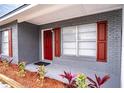 Front entrance with red door, gray brick, and red shutters at 115 7Th Jpv St, Winter Haven, FL 33880