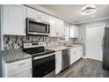 Modern kitchen with white cabinets, granite counters, and stainless steel appliances at 115 7Th Jpv St, Winter Haven, FL 33880