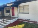 Front view of a charming white brick house with red door and landscaping at 1415 Lotela Ave, Lakeland, FL 33805