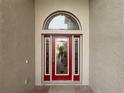 Elegant red front door with arched window and glass panels at 4193 Limerick Dr, Lake Wales, FL 33859