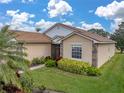 Tan house with brown roof, lush landscaping, and walkway at 5185 Pebble Beach Blvd, Winter Haven, FL 33884