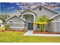 Gray house with double doors, palm tree, and walkway at 1932 Southern Dunes Blvd, Haines City, FL 33844