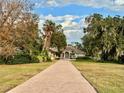 Inviting single-story home with a long brick driveway and mature trees lining the yard at 1006 W Lake Hamilton Dr, Winter Haven, FL 33881