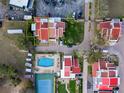 An aerial view of a community showcasing the beautiful pool, tennis court, and red-roofed condos surrounded by lush greenery at 1 Casarena Ct, Winter Haven, FL 33881