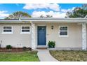 Inviting entrance featuring a blue front door, decorative columns, and manicured landscaping at 106 Lake Sears Dr, Winter Haven, FL 33880