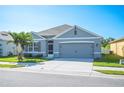 Inviting single-story home features a well-kept lawn, a two-car garage, and tropical palm tree at 144 Emanuelle Dr, Winter Haven, FL 33884