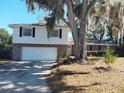 Charming two-story home with a brick facade and an attached garage, framed by a large shade tree at 148 Lake Otis Rd, Winter Haven, FL 33884