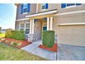 Home's front porch with stone accents, blue door, an attached two-car garage, and professional landscaping at 1510 Shorewood Dr, Auburndale, FL 33823