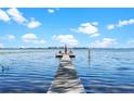 Picturesque view of a dock on a calm lake with seating and an umbrella for relaxing at 2841 Country Club N Rd, Winter Haven, FL 33881