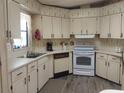 Traditional kitchen featuring white cabinets, laminate countertops, and white appliances at 6059 Southern Oaks Se Dr, Winter Haven, FL 33884