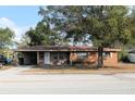 Cozy brick house featuring a covered carport and a well-maintained yard with a large shade tree at 807 S 1St St, Lake Wales, FL 33853