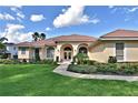 Attractive home with arched entryway, double doors, beautiful landscaping, and well-maintained lawn at 105 Wyndham Dr, Winter Haven, FL 33884