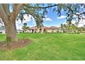 A wide shot showcases a lovely home with a green lawn and mature landscaping beneath a partly cloudy sky at 105 Wyndham Dr, Winter Haven, FL 33884